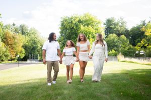 Group walking together through a sunny green field wearing white outfits.