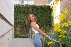 Casual urban photoshoot against brick walls with yellow flowers and natural lighting.