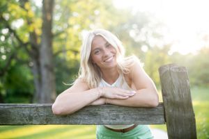 Person relaxing on rustic wooden fence during sunset photoshoot.