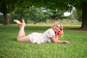 Person lying in green grass during a summer photoshoot outdoors.