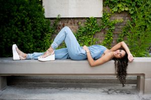 Person lounging on outdoor concrete benches in an urban garden setting.