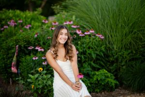 Dreamy outdoor portrait session in a garden with pink flowers and tall grass at golden hour.