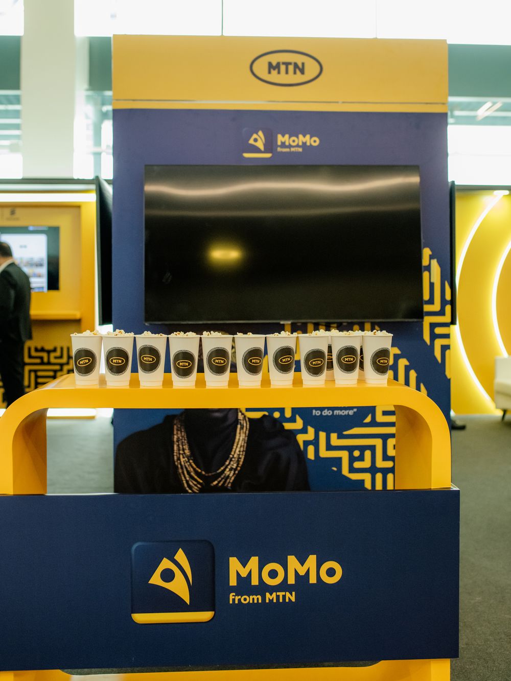 Interior view of MTN MoMo retail store with yellow and blue branded counters and signage displays.