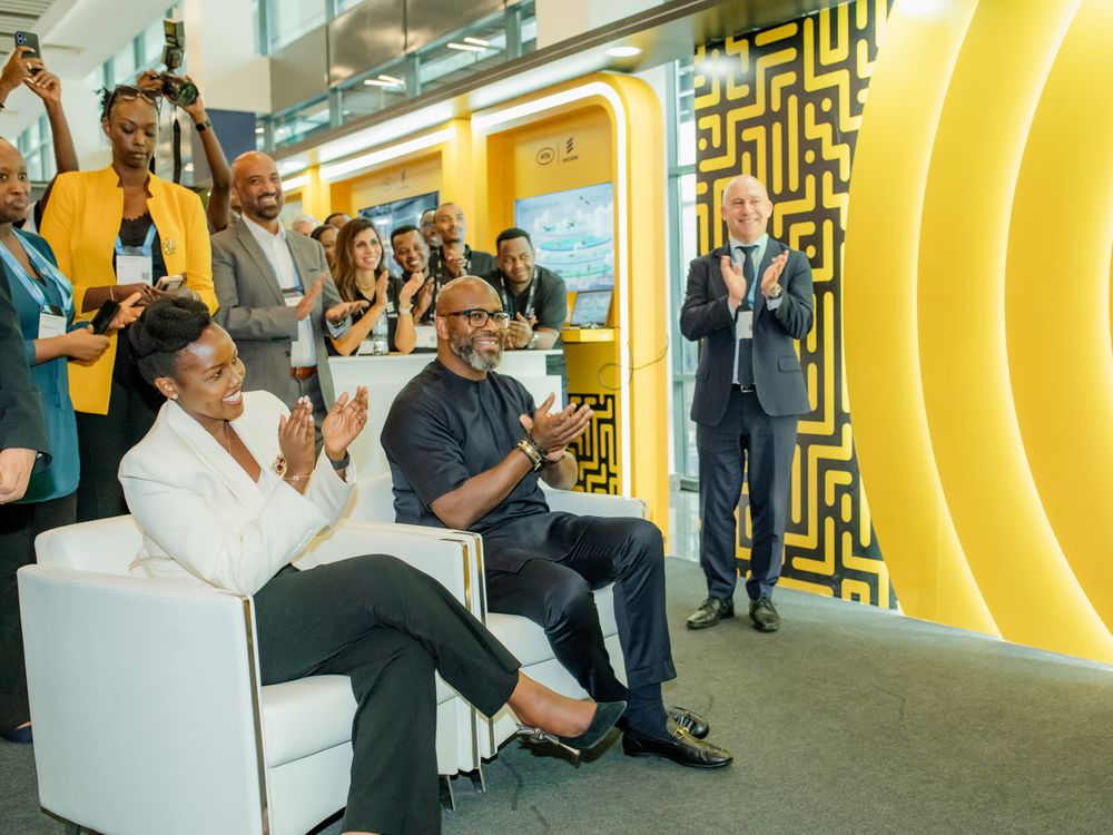 Business professionals gather in a modern office space with vibrant yellow walls and geometric patterns.