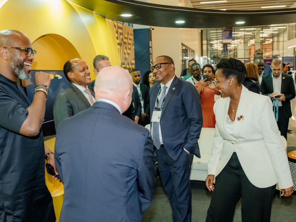 People in business attire networking in a corporate hallway with bright yellow design elements.