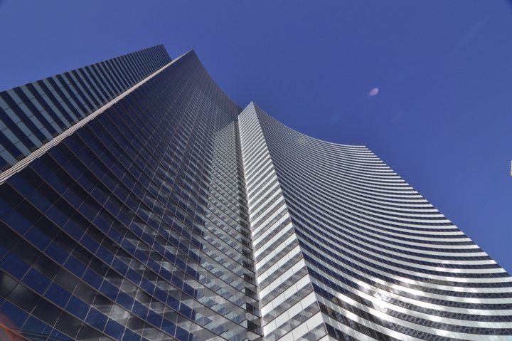 Low angle view of a modern curved glass skyscraper reflecting blue sky in Las Vegas.