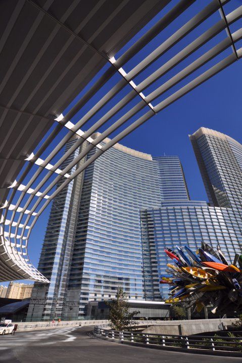 Modern architectural complex with curved glass towers and colorful sculpture under blue sky in Las Vegas.