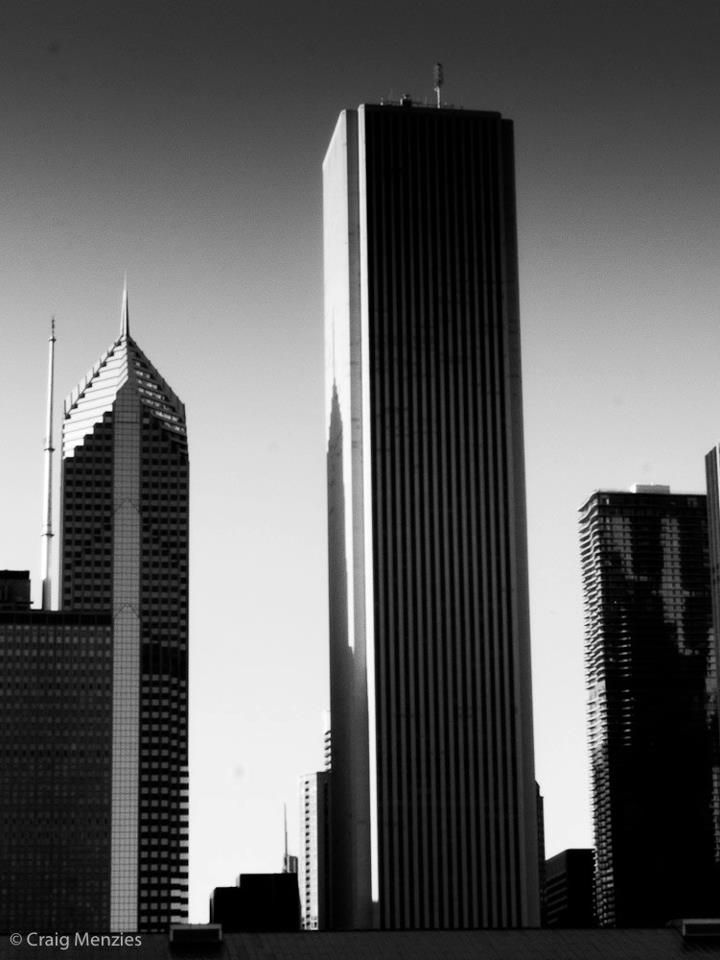 Dramatic black and white skyline view of tall skyscrapers against a clear sky in a major city.