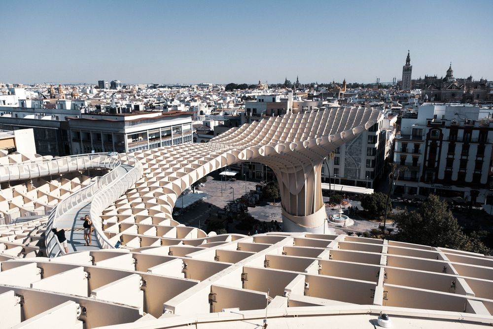 Close-up view of the Metropol Parasol structure in Seville, Spain, featuring its distinctive latticed wooden canopy against a blue sky.
