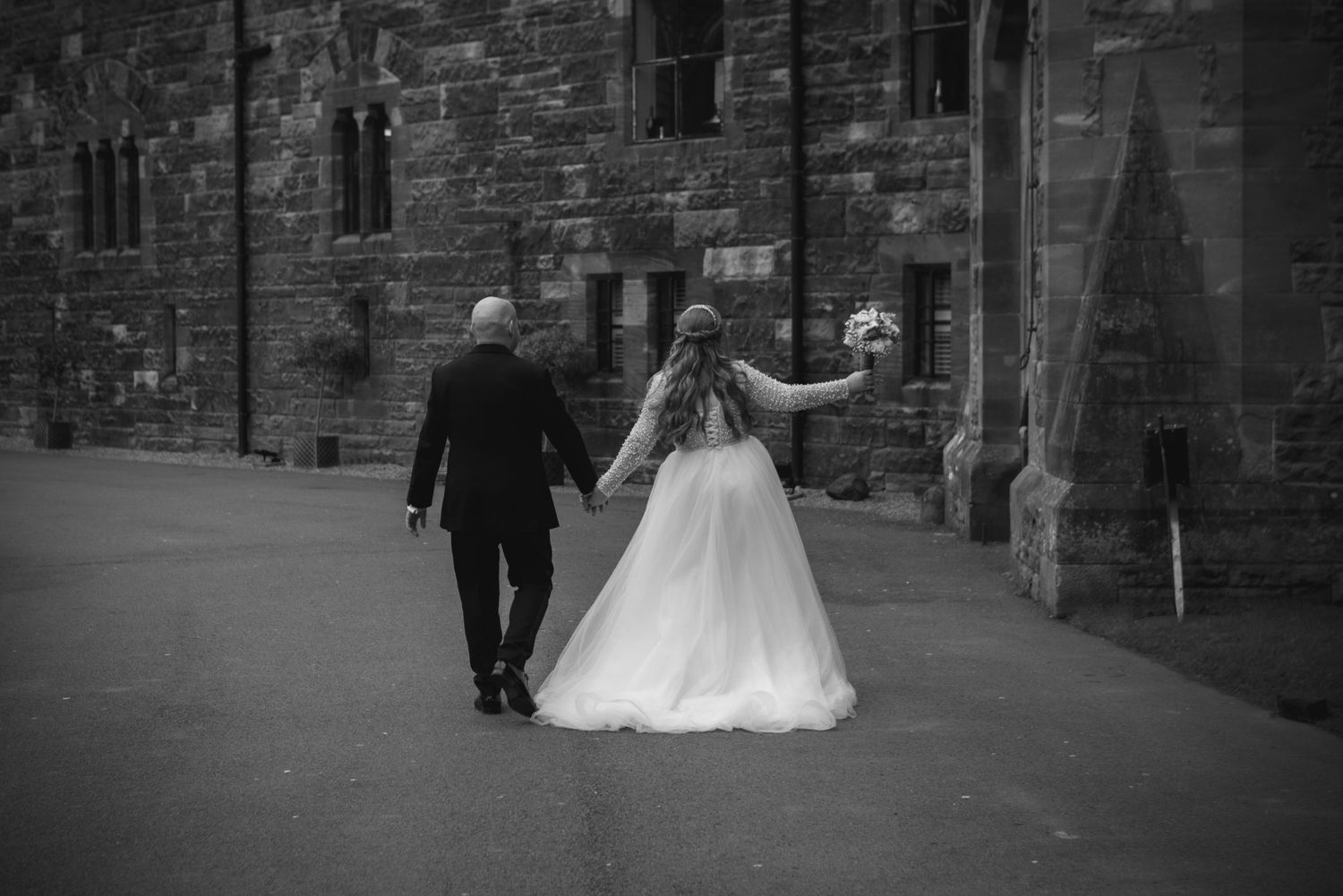 A tender wedding moment captured in a meadow with a white lace dress and grey suit against a natural landscape backdrop.
