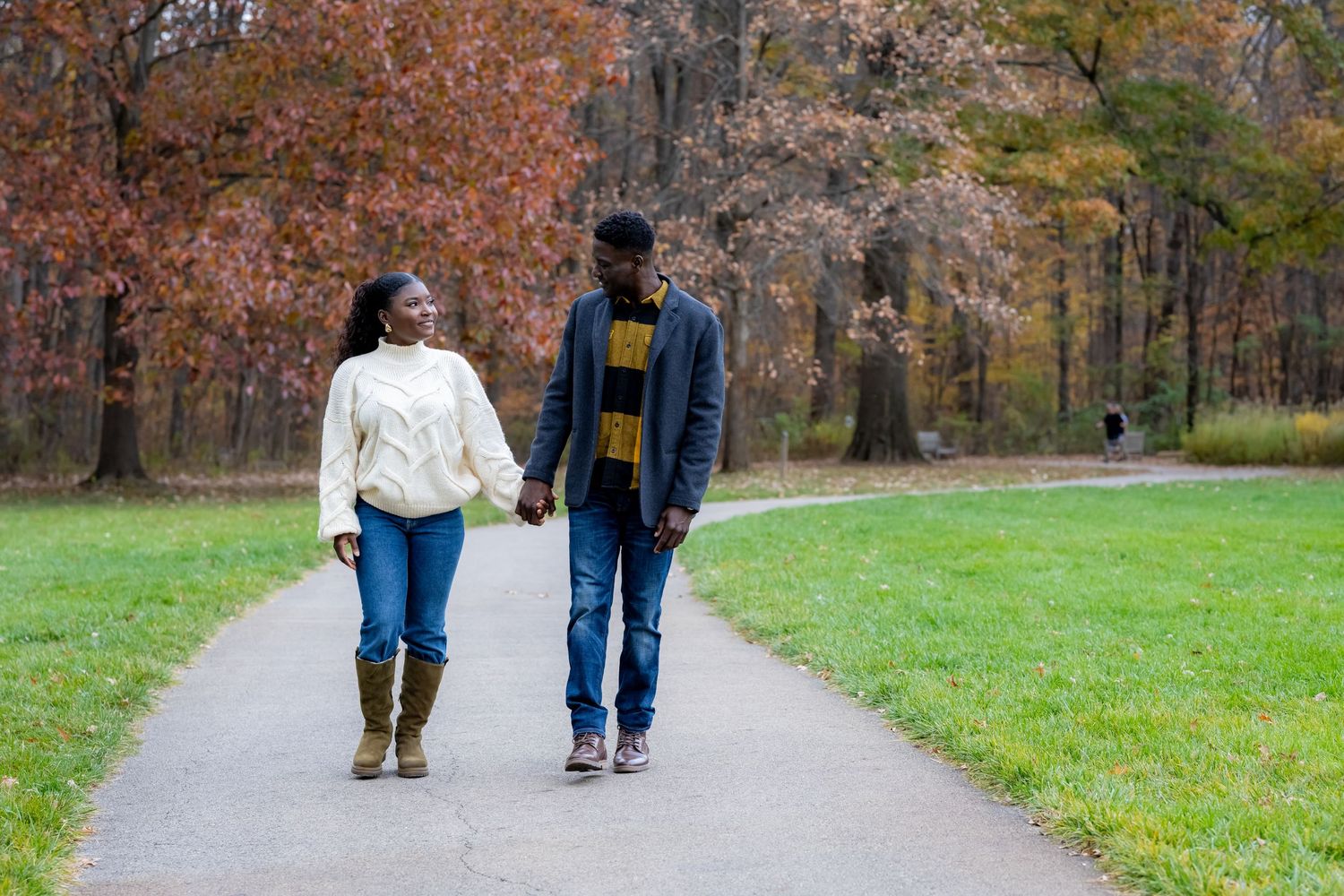 People walking along an autumn path surrounded by trees with colorful fall foliage.