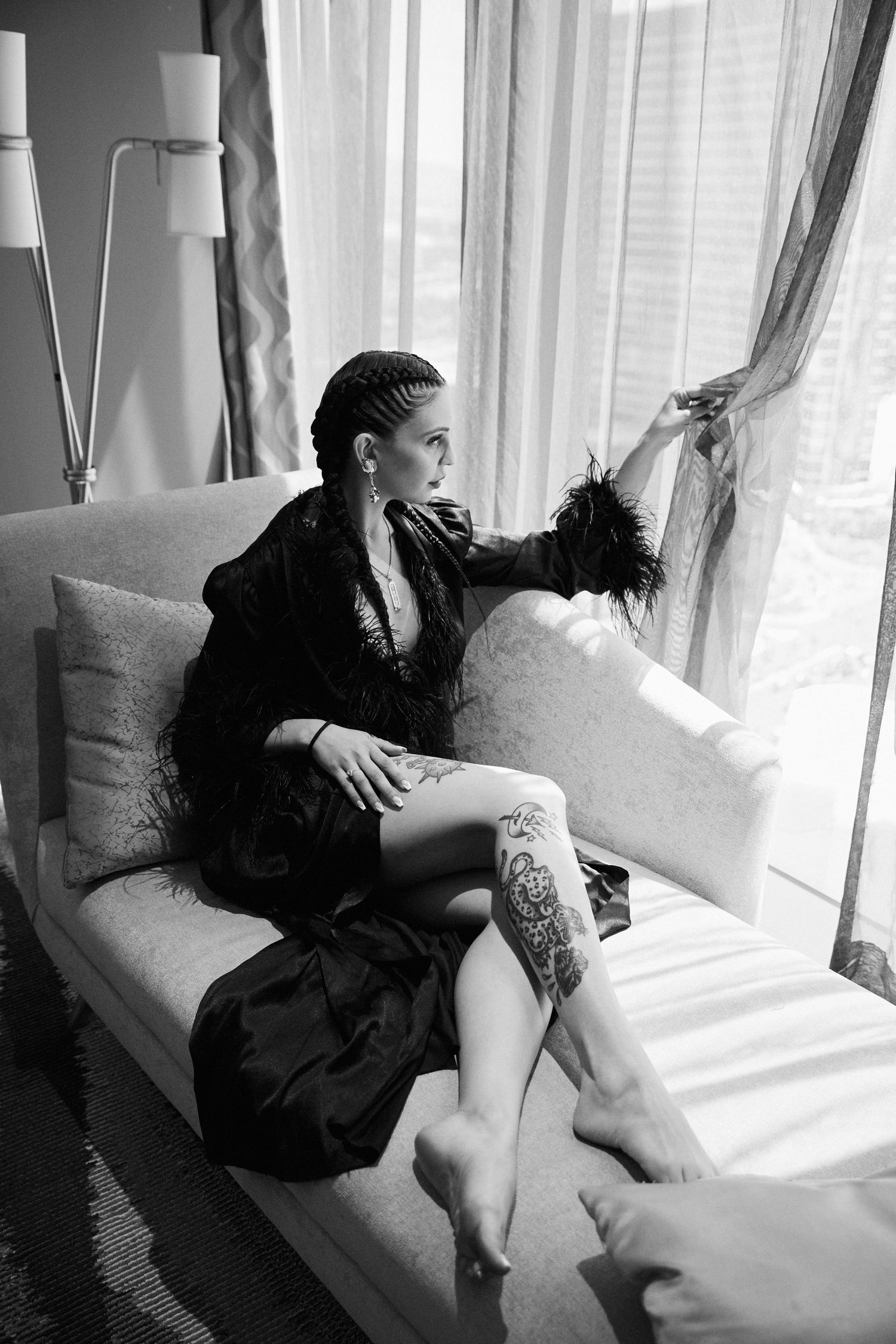 Black and white boudoir photo series in sunlit room with white curtains.