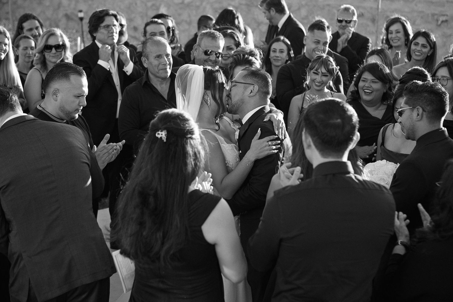Black and white photo of wedding guests dancing and celebrating at a reception.