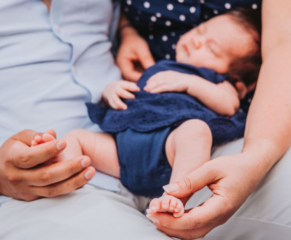 Close-up of tiny baby feet and hands on blue fabric.