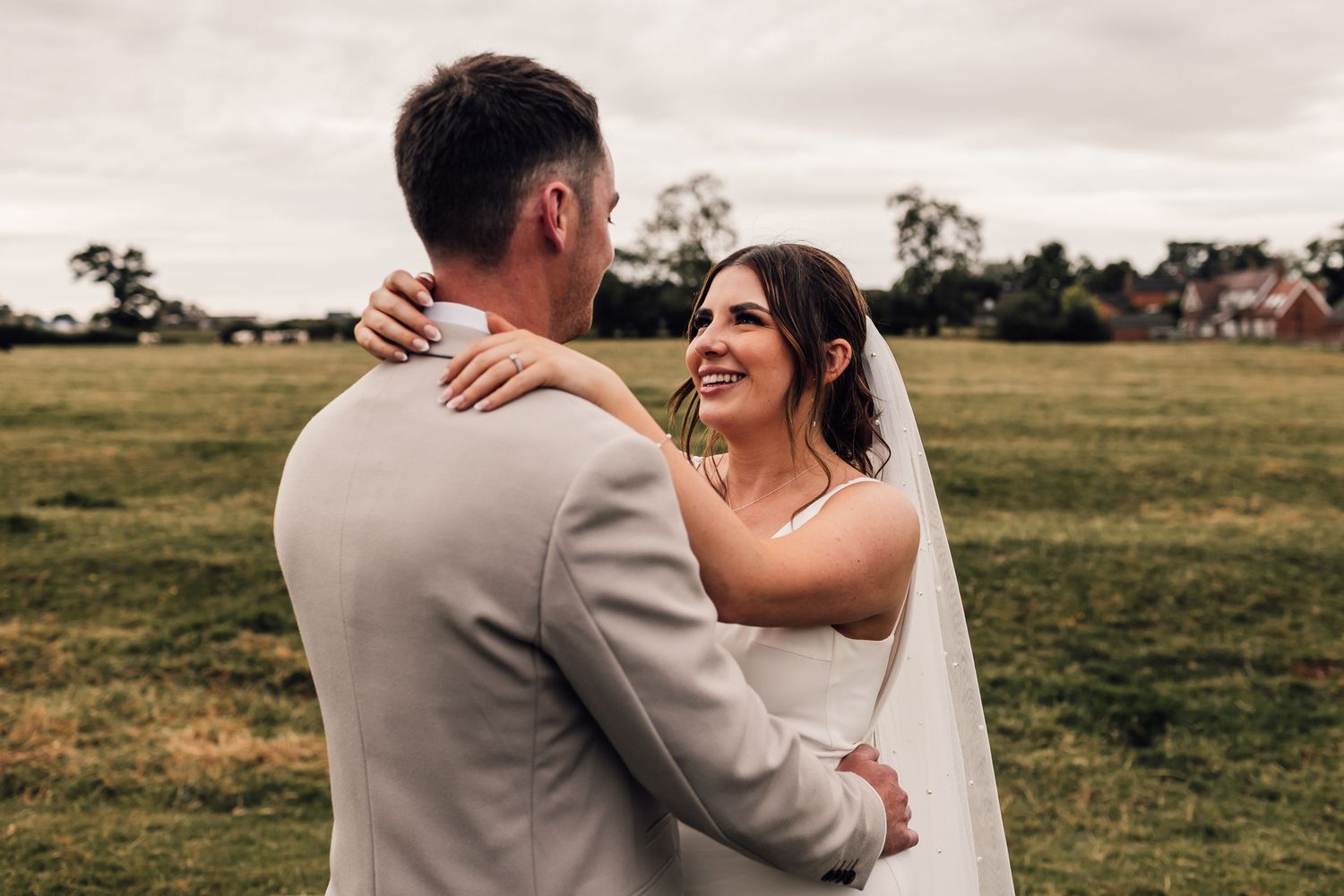 A romantic moment between newlyweds in a field during their countryside wedding.