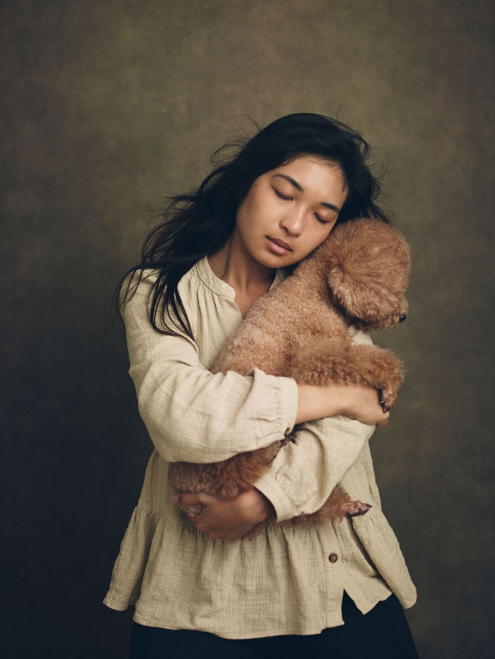 Artistic portrait series showing gentle embrace with teddy bear against moody dark backdrop.