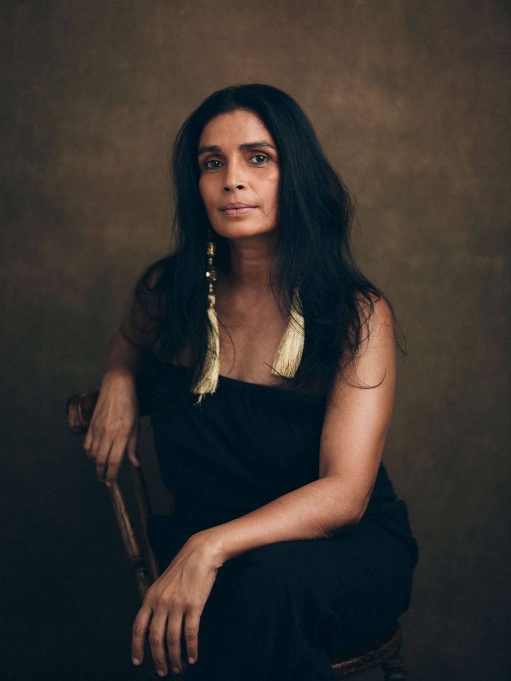 Dramatic portrait series with person in black outfit against textured brown background.