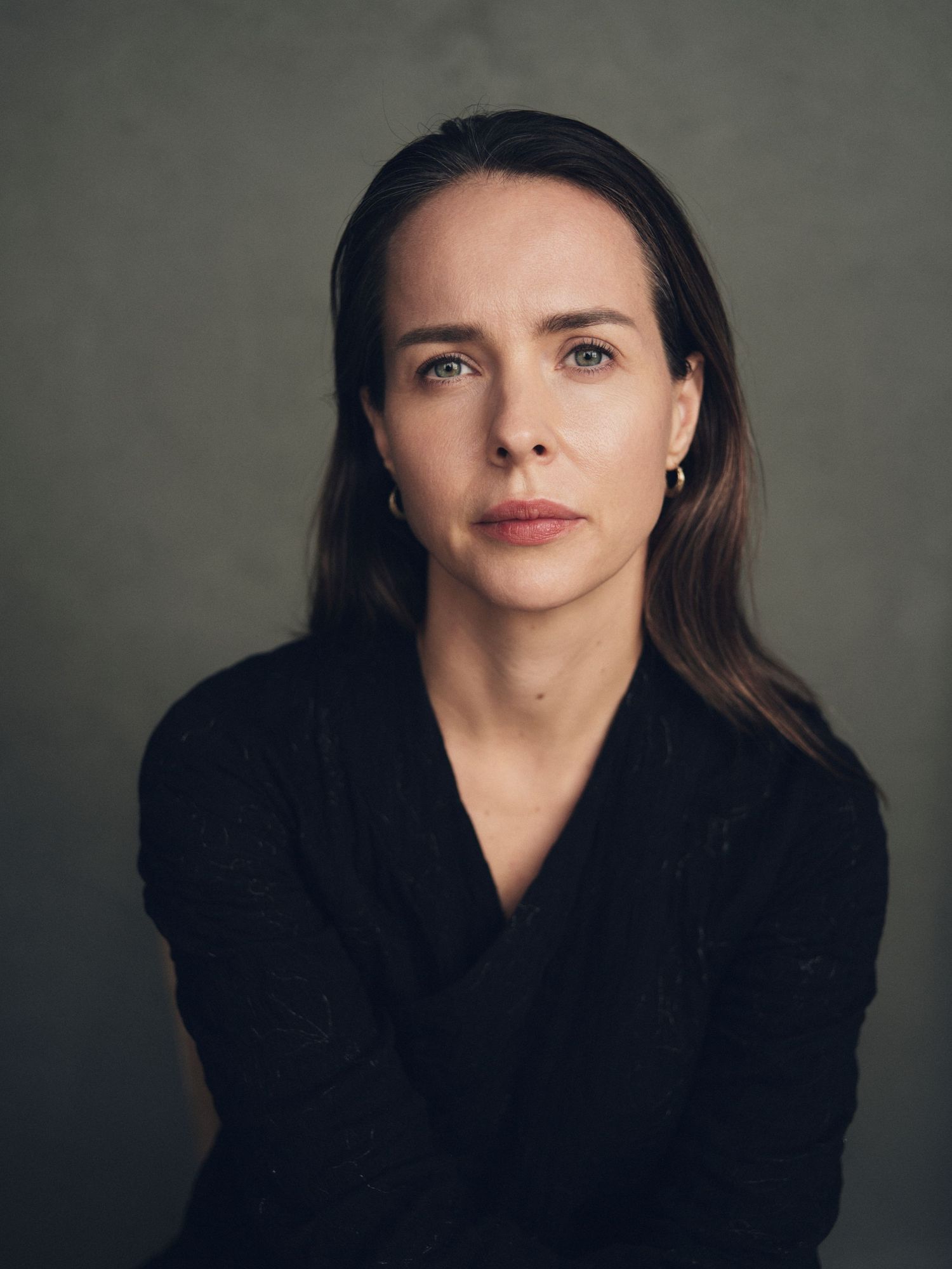 Moody studio portraits with dramatic lighting against dark textured background.