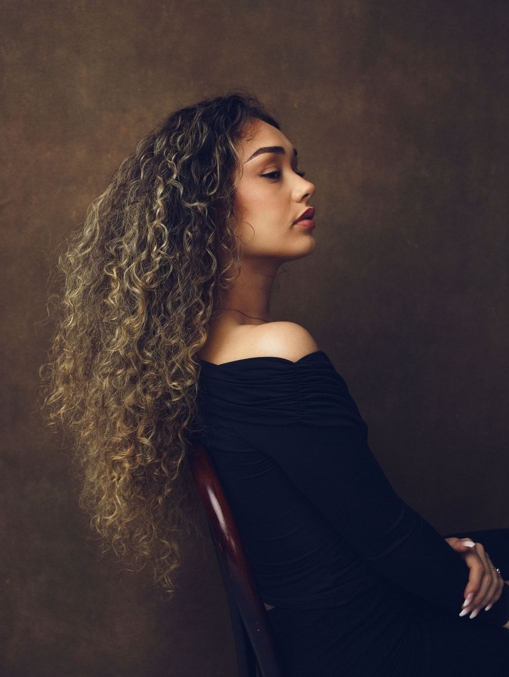 Artistic portrait series featuring curly hair and black clothing in moody lighting.