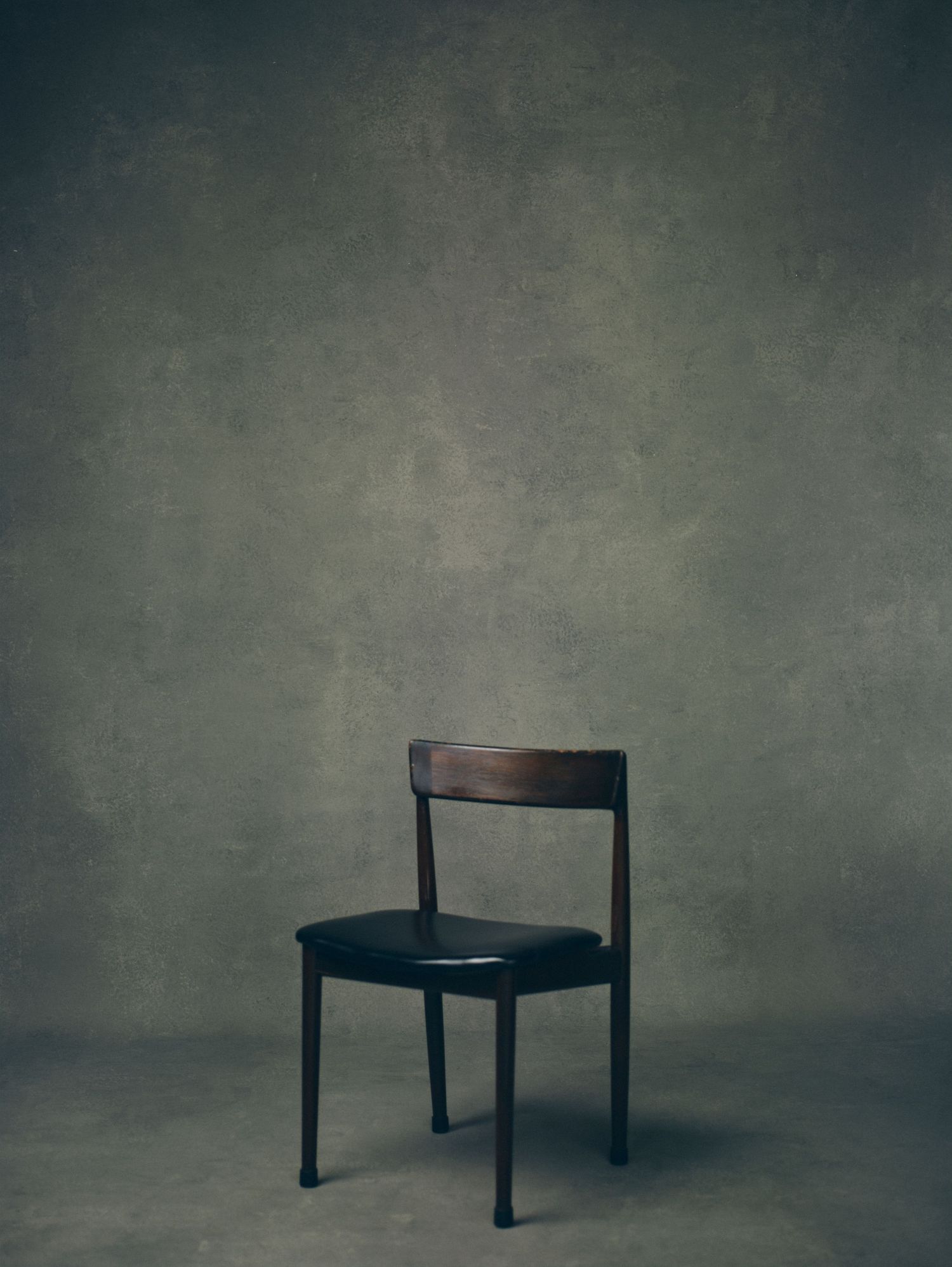 Minimalist series showing empty black chairs against textured gray background.