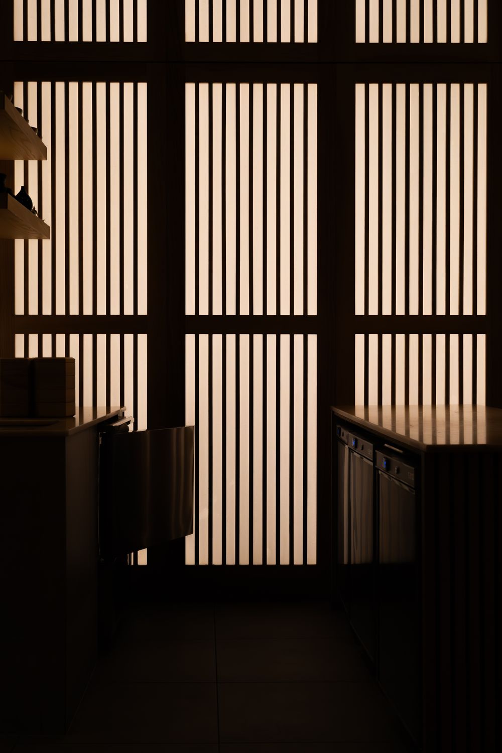 Minimalist Japanese interior with backlit shoji screens creating geometric patterns of light and shadow.