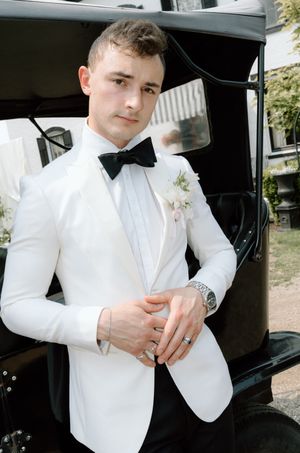 Young person in formal white tuxedo jacket and bow tie getting ready in a vehicle for a special occasion.