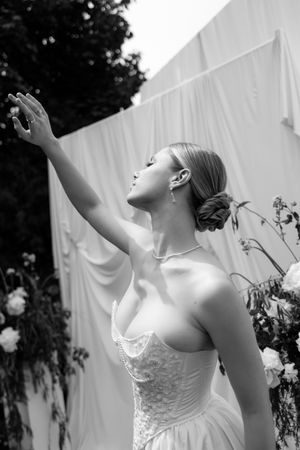 A bride in a white wedding dress poses joyfully with raised arms in an artistic series of black and white photos.