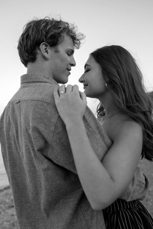 Black and white romantic portrait of a couple in intimate embrace sharing a tender moment outdoors.