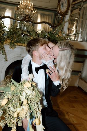 A romantic dip and kiss moment at an elegant wedding reception with chandeliers and floral decor.
