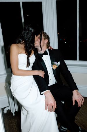 A couple in formal wedding attire dance together at a reception, with the bride in white and groom in black tuxedo.