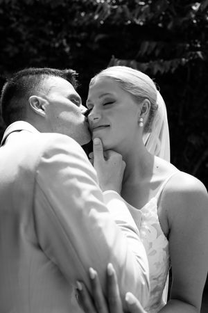 A romantic black and white sequence showing a tender kiss between newlyweds at a wedding ceremony.