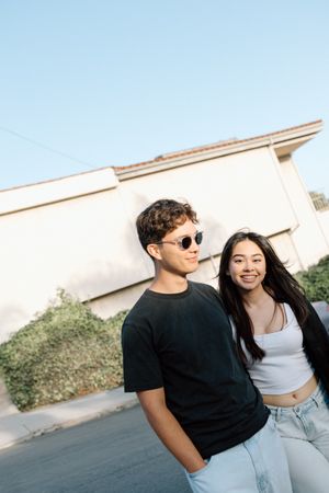 A couple in casual outfits share affectionate moments against a white wall in a series of photos.