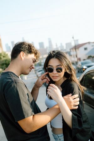 A playful couple shares a loving moment against a Los Angeles skyline in the background.