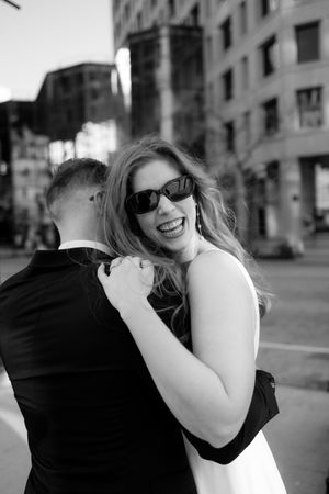 Black and white photo of a couple embracing and laughing in an urban setting.