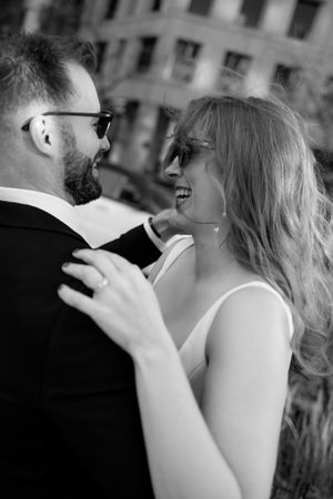 Couple sharing a joyful moment together in black and white against city architecture.