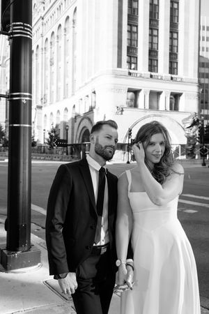 A black and white urban wedding portrait with classic architecture in the background.