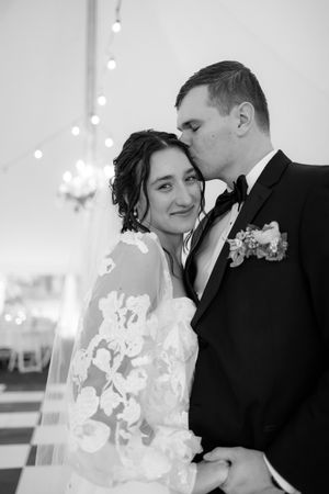 A tender black and white wedding moment captured under a chandelier.