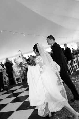 A romantic first dance between newlyweds on a checkered dance floor.