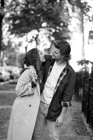 A couple shares an intimate moment outdoors in black and white photography.