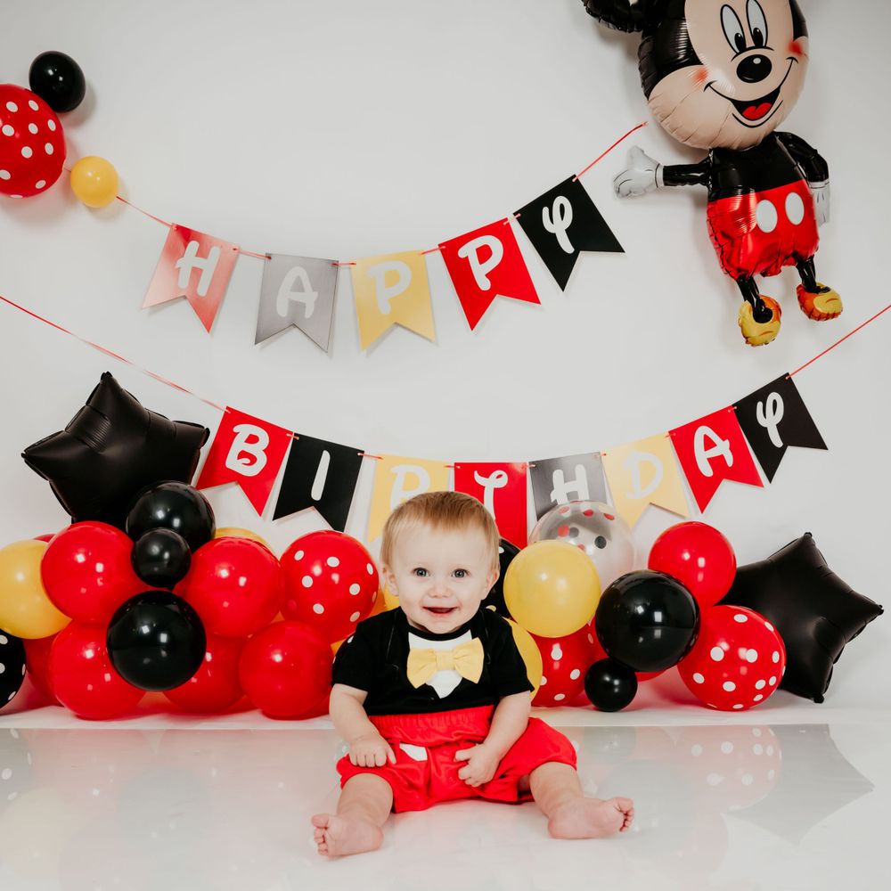Mickey Mouse themed birthday setup with red and black balloons and decorative banners.