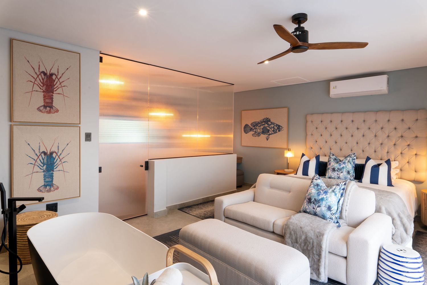 Coastal-themed living room with lobster artwork, cream sofa, blue accents, and ceiling fan.