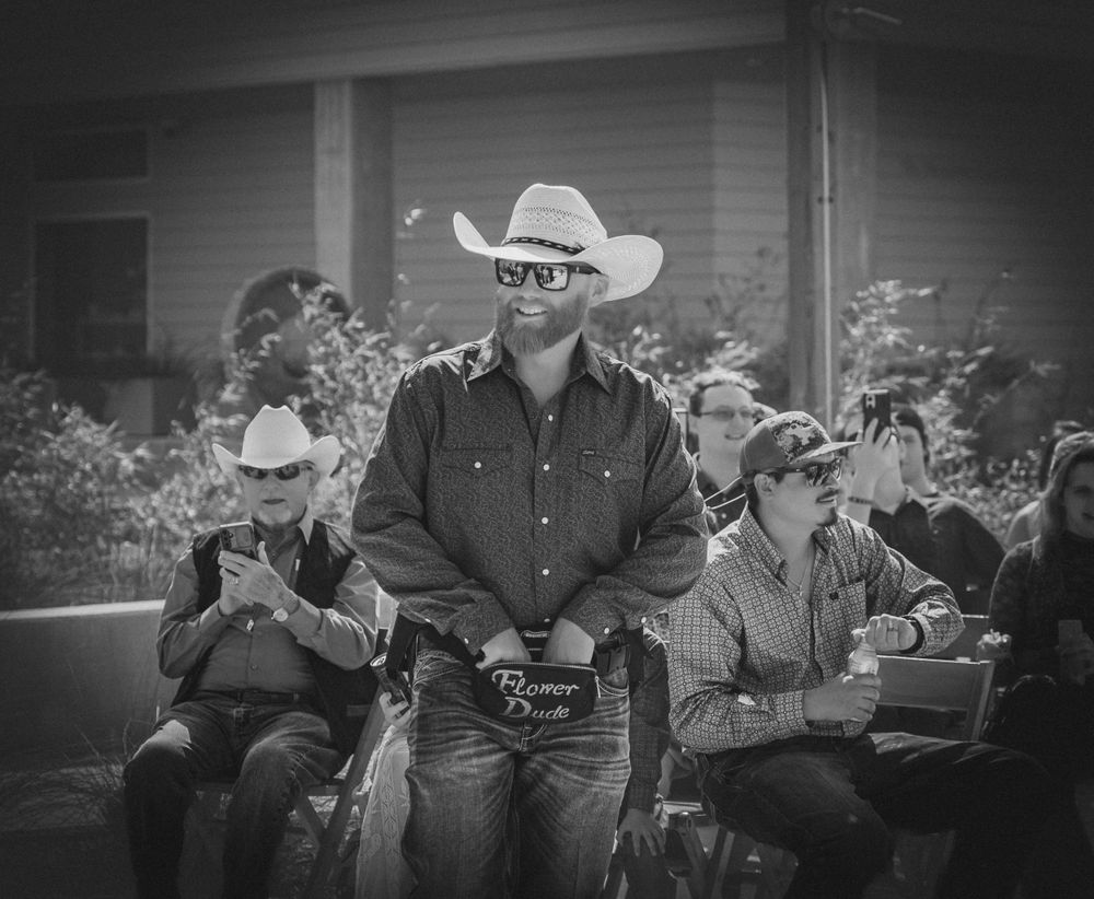 Vintage black and white photo showing people at a western event with someone wearing a cowboy hat and denim.