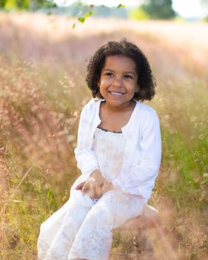 A portrait in a sunny field wearing a white lacy dress.