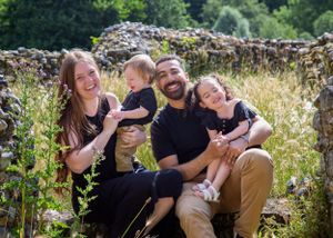 Happy family enjoying playful moments together in a lush garden setting.
