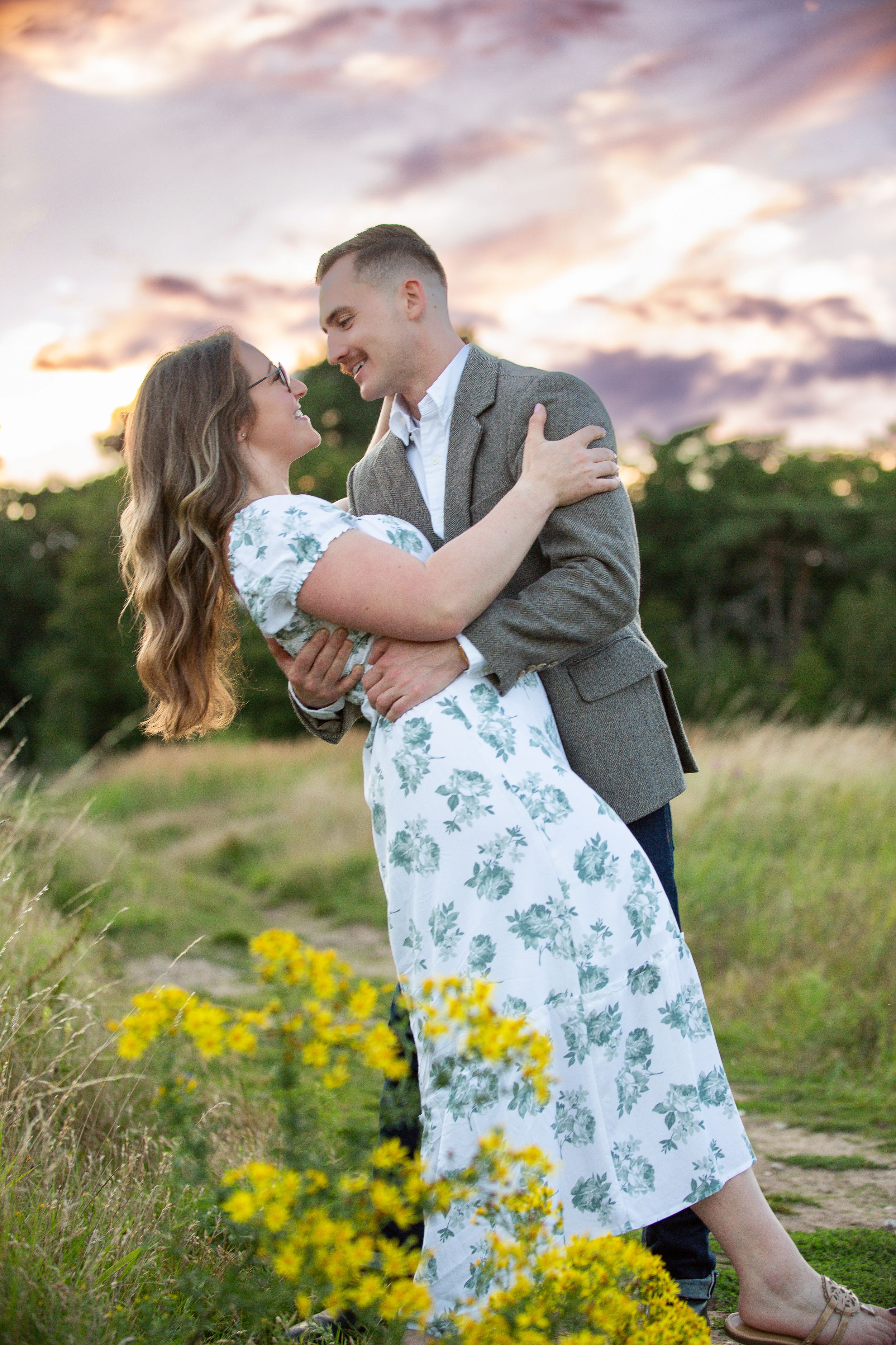 Romantic couple embracing in a field of yellow wildflowers at sunset.