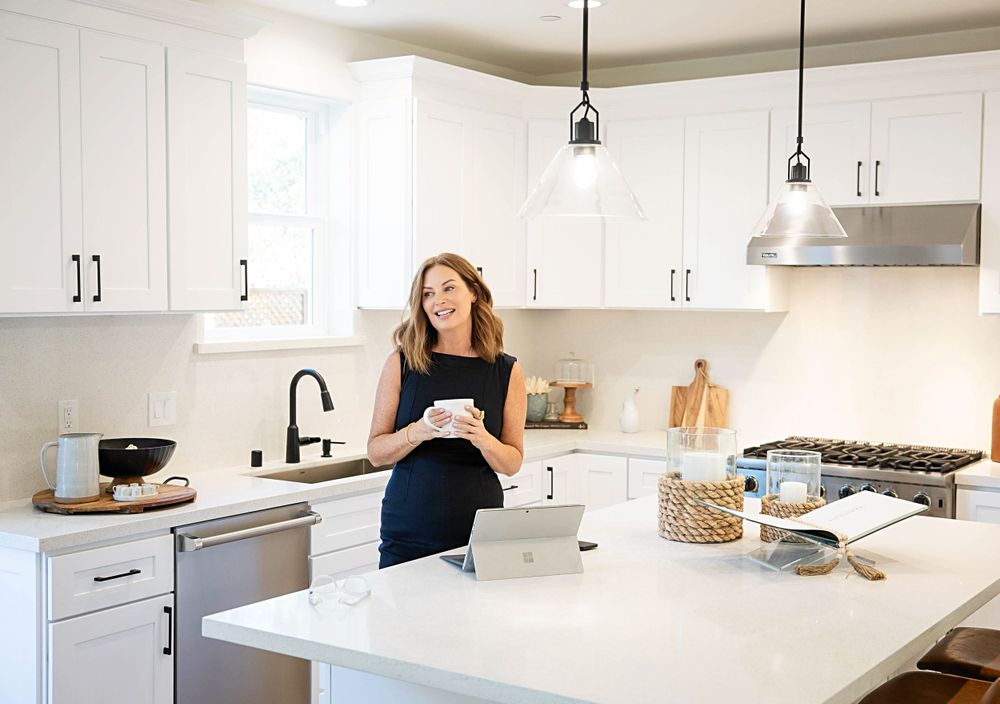 Modern bright white kitchen interior with marble countertops, pendant lights and stainless steel appliances.
