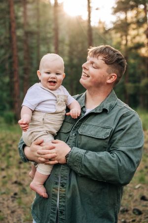 A joyful outdoor portrait captured in a sunlit pine forest.