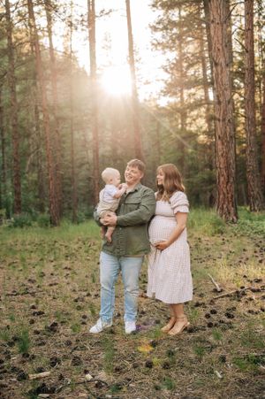 A loving family portrait captured in a sunlit forest setting.
