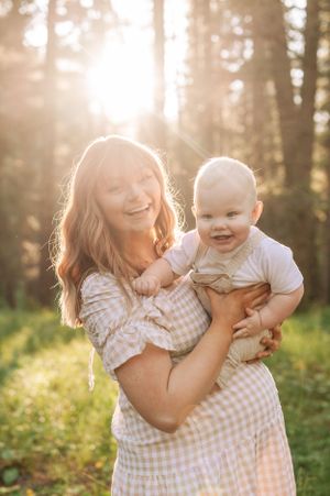 Candid forest portrait showing pure joy between a parent and baby during golden hour.