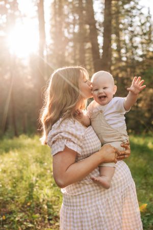 Sweet interaction between parent and baby in a sunlit forest setting.